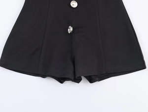 Close-up of black sleeveless romper featuring decorative sparkling crystal buttons