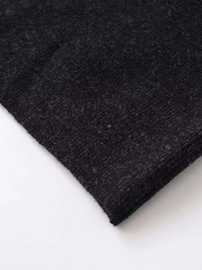 Detailed macro view of dark grey knit texture and asymmetric hemline fabric quality