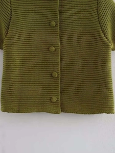Dettaglio del cardigan in maglia verde oliva con trama a costine e bottoni coordinati