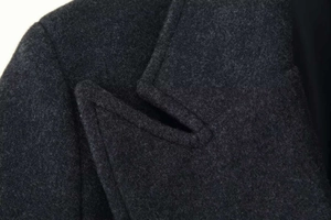 Dettaglio della texture in lana antracite e cuciture sul bavero del cappotto lungo