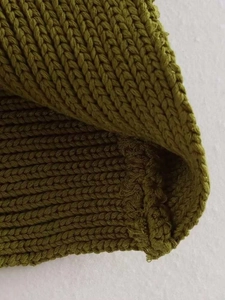 Macro del tessuto a maglia a coste verde oliva che mostra cuciture fini e spessore