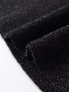 Close-up of soft black knit fabric texture and ribbed hem detail on knitted skirt