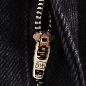 Detailed close-up of high-waist black straight jeans with a vintage metal zipper pull