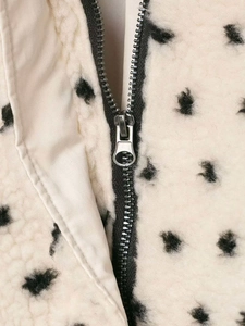 Close-up of soft white fleece jacket featuring black polka dots and silver metal zipper detail