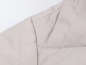 Detailed macro view of beige quilted winter jacket fabric and fine stitching quality