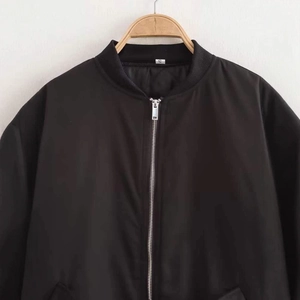 Classic black bomber jacket featuring ribbed collar and silver metal zipper hanging on hanger