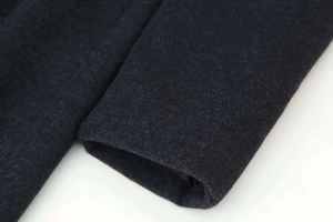 Dettaglio della manica del cappotto di lana grigio scuro che mostra la trama del tessuto