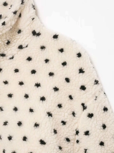 Detailed close-up of cream fleece jacket featuring black polka dot pattern and soft texture