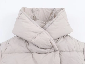 Detail of light beige hooded puffer coat showing the high collar and quilted texture