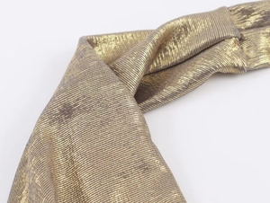 Macro shot of metallic golden fabric with fine horizontal woven texture on the halter top