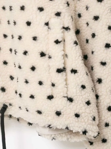 Macro view of cream polar fleece fabric with black polka dots and drawstring detail