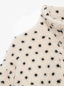 Detail of white fleece jacket with black polka dot pattern and high collar neck