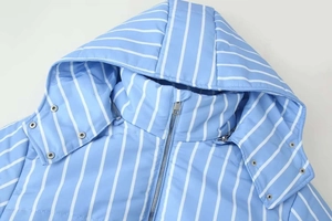 Detail of blue and white striped winter jacket featuring metal zipper and snap buttons