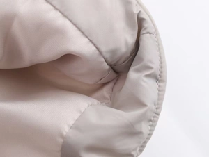 Macro view of light beige puffer jacket showing smooth fabric and neat stitching detail