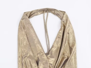 Close-up of golden metallic halter top showing shimmering pleat detail and fabric texture