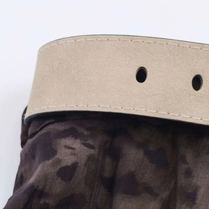Close-up of beige leather belt with circular perforations on camouflage print midi skirt