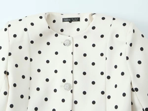 Detailaufnahme eines cremefarbenen Blazers mit schwarzen Punkten und Strassblumen-Knopf