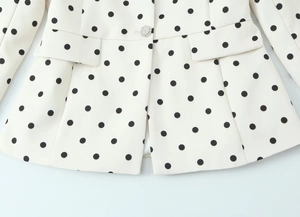 Detail der weißen Polka-Dot-Jacke mit Pattentaschen und einem funkelnden Kristallknopf