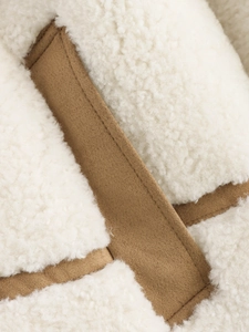 Détail d'une veste en polaire sherpa blanche avec passepoil en daim marron de qualité