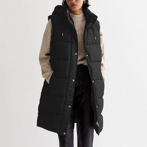 Detail of hooded black long padded vest with metallic snaps and quilted texture