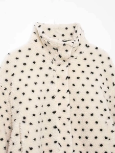 Detailed texture of white polka dot fleece jacket with a stand collar and soft fuzzy fabric
