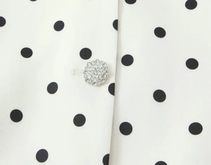 Nahaufnahme eines eleganten Silber-Strass-Knopfes auf weißem Polka-Dot-Blazer