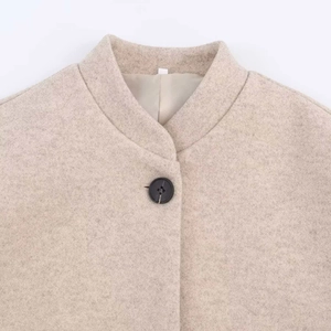 Détail d'un manteau en laine avoine avec col montant et bouton noir de haute qualité