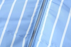 Close-up of silver metal zipper and blue vertical striped quilted fabric on winter puffer coat
