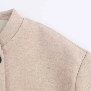 Gros plan sur le col montant et la texture en laine d'un long manteau beige