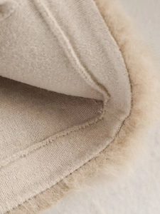 Detailed macro view of soft beige faux fur coat with high-quality interior stitching