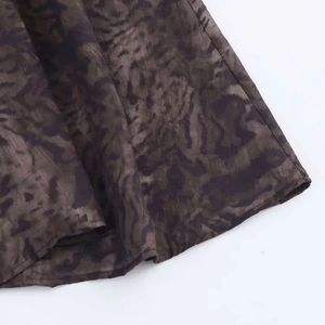 Detailed close-up of dark abstract printed midi skirt fabric with smooth hem stitching