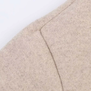Détail de la texture du tissu en laine beige montrant la couture et la qualité des fibres