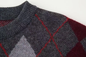 Detail of round neckline and argyle knit pattern on a relaxed oversized sweater