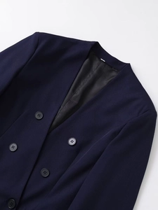 Détail du blazer bleu marine à col en V montrant les boutons et la texture du sergé