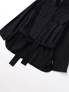 Detail eines schwarzen langärmeligen Funktionshemdes mit Brusttaschen und Bindegürtel