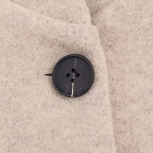 Gros plan sur la texture du manteau en laine beige et le détail du bouton noir