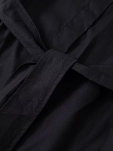 Detail der Taillenbindung und feinen Köperstruktur einer schwarzen Langarmbluse