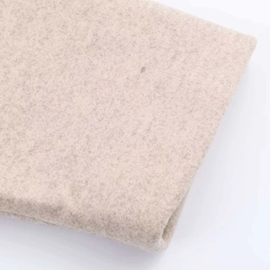 Vue macro détaillée du tissu en laine beige montrant la finition feutrée douce du manteau