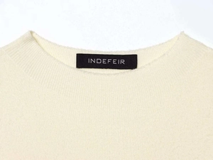 Close-up of cream knit sweater neckline with fine ribbed texture and brand label