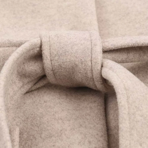 Détail d'un manteau en laine beige montrant les passants et la texture du tissu doux