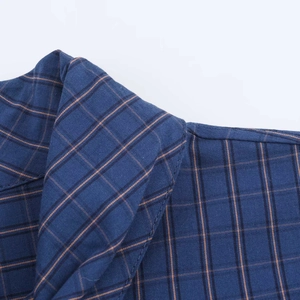 Detailed view of the dark blue and orange plaid cotton shirt collar and stitching