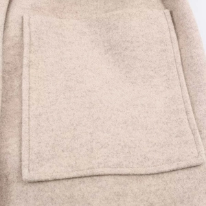 Détail du manteau en laine avoine avec une grande poche plaquée et une texture douce