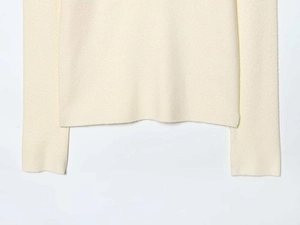 Detailed close-up of cream knit sweater hem and cuffs showing soft ribbed texture