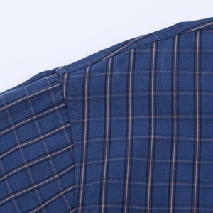 Detail of reinforced shoulder stitching on a navy blue and orange plaid cotton shirt