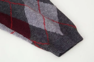 Detail of argyle pattern knit sweater with grey and burgundy diamonds and ribbed cuff
