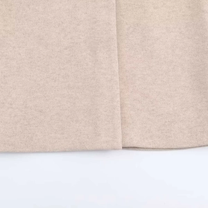 Détail de l'ourlet du manteau en laine beige montrant les coutures et la texture du tissu