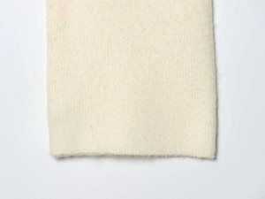 Detailed macro view of the finely knitted cuff on a minimalist cream white sweater