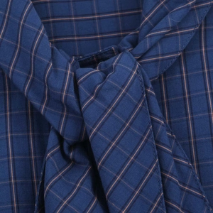 Macro detail of navy blue plaid fabric with orange checks and fine stitching for shirts