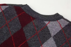 Detailed close-up of a ribbed crew neck on an argyle knit sweater with red accent stitching