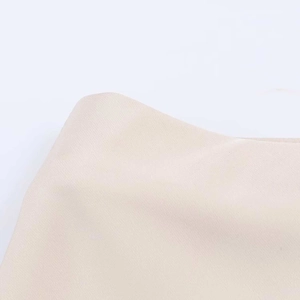 Close-up of beige satin fabric midi skirt showing smooth texture and seamless edge